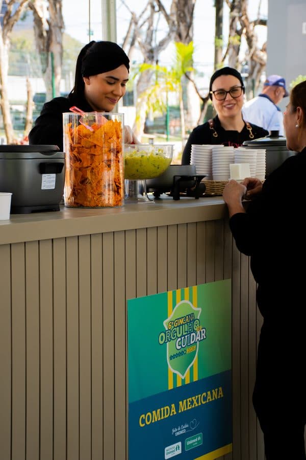 Promotoras da Glow servindo colaboradores em gincana interna com placa personalizada